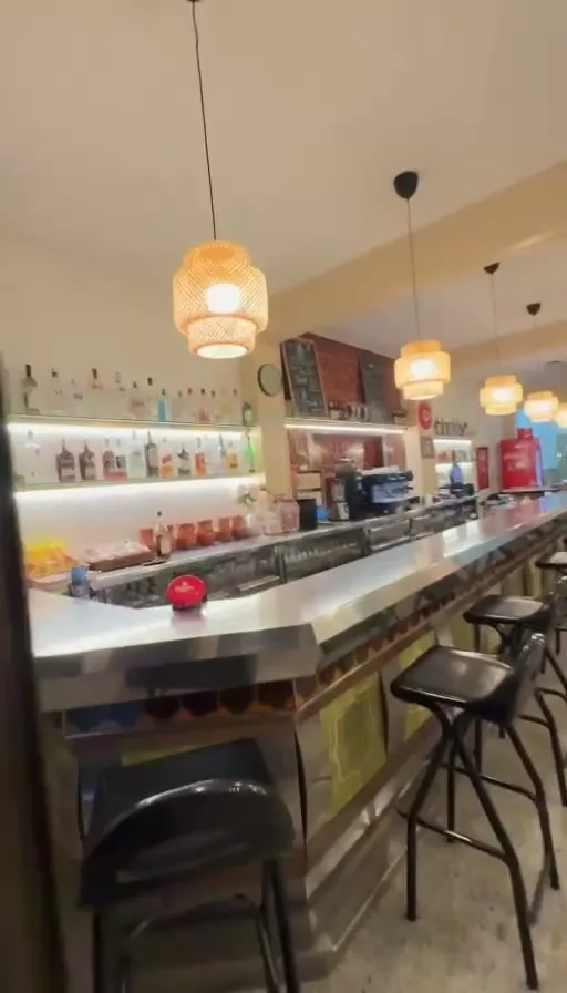 Interior del bar con barra y taburetes altos
